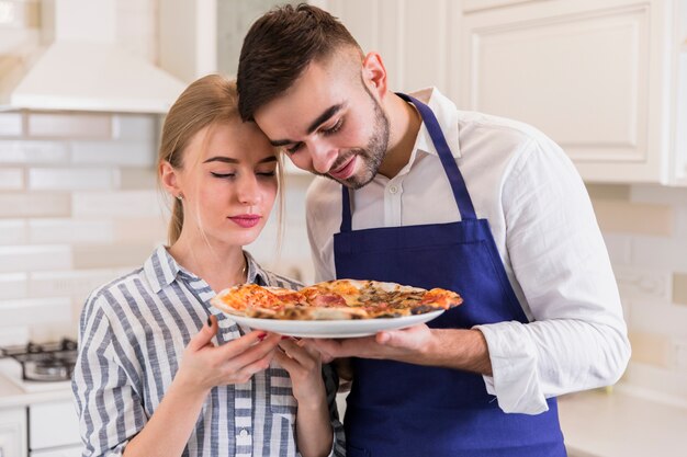 Para wącha pizzę na talerzu