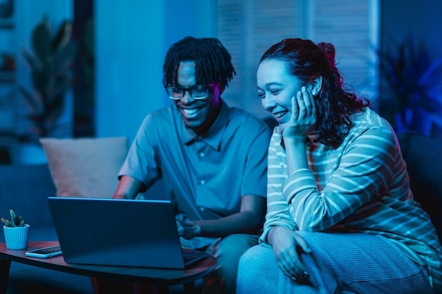 Para za pomocą laptopa razem na kanapie w domu