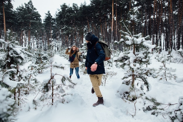 Para zakochanych zabawy i gry śnieżki w snowy sosnowym lesie