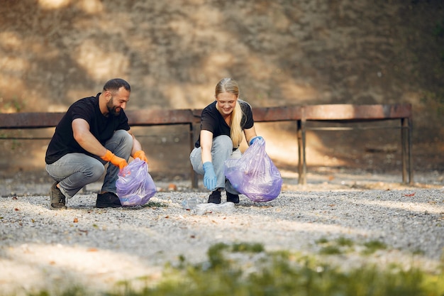 Bezpłatne zdjęcie para zbiera śmieci w workach na śmieci w parku
