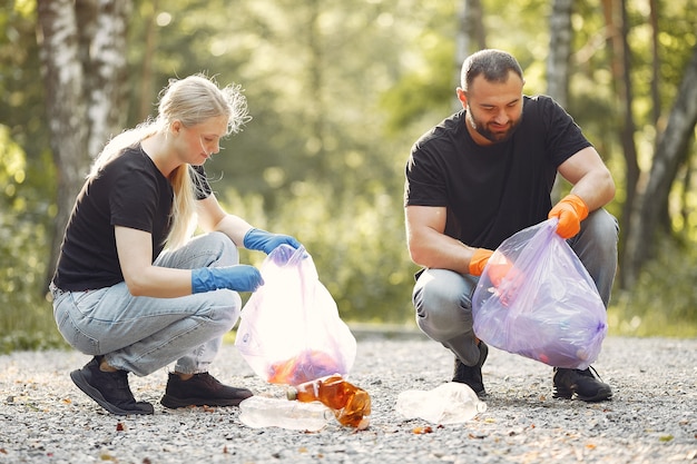 Para zbiera śmieci w workach na śmieci w parku