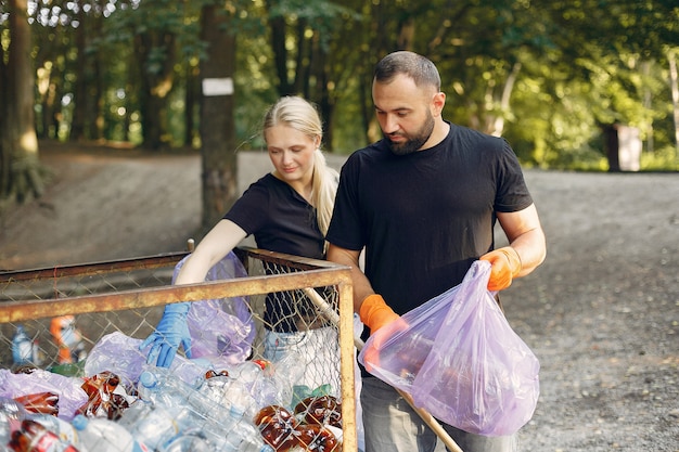 Para zbiera śmieci w workach na śmieci w parku