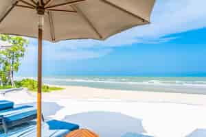Bezpłatne zdjęcie parasol i krzesło na plażowym dennym oceanie z niebieskim niebem i biel chmurą