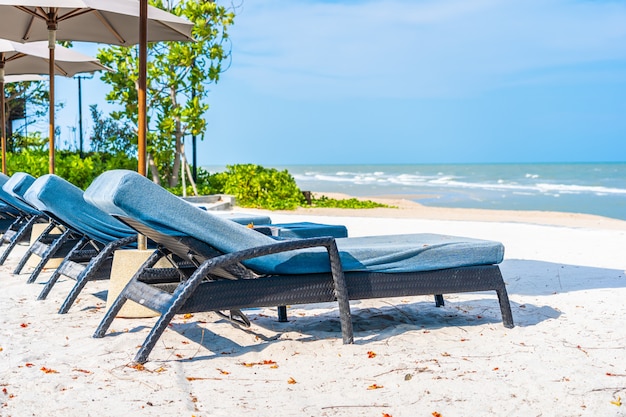 Parasol i krzesło na plażowym dennym oceanie z niebieskim niebem i biel chmurą