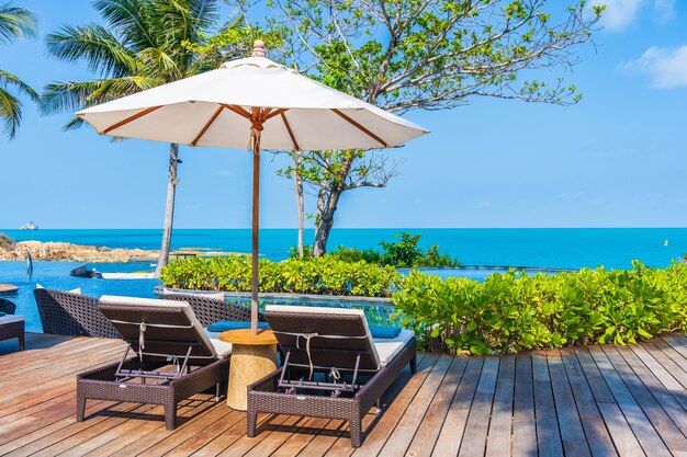 Parasol i krzesło wokół odkrytego basenu w hotelowym kurorcie z widokiem na morze na wakacje w podróży