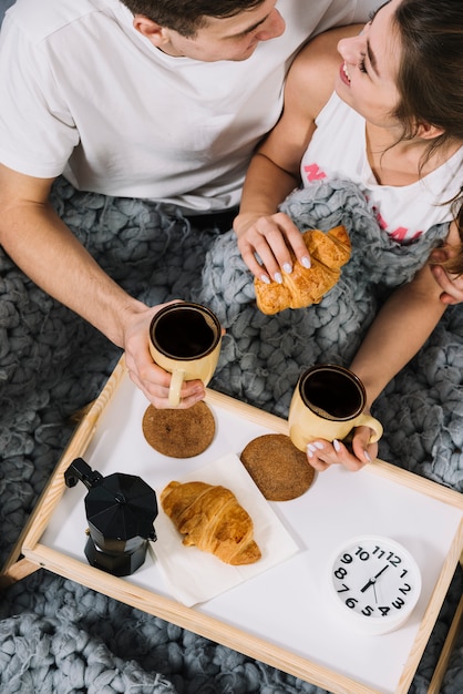 Bezpłatne zdjęcie pary łasowania croissants z kawą w łóżku