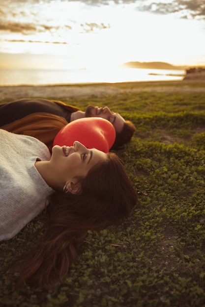 Pary lying on the beach na trawie z czerwonym serce balonem