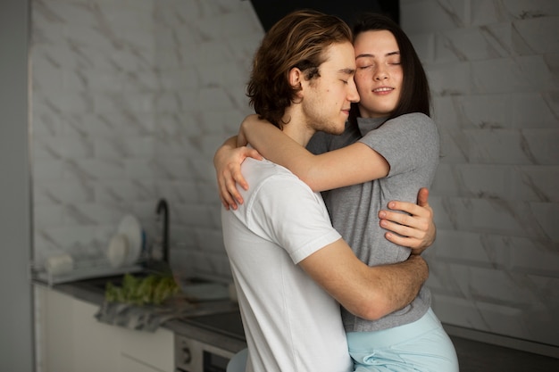 Bezpłatne zdjęcie pary przytulenie i ono uśmiecha się w kuchni
