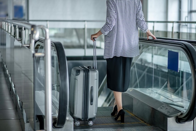 Pasażer lotniska z bagażem jadący ruchomymi schodami