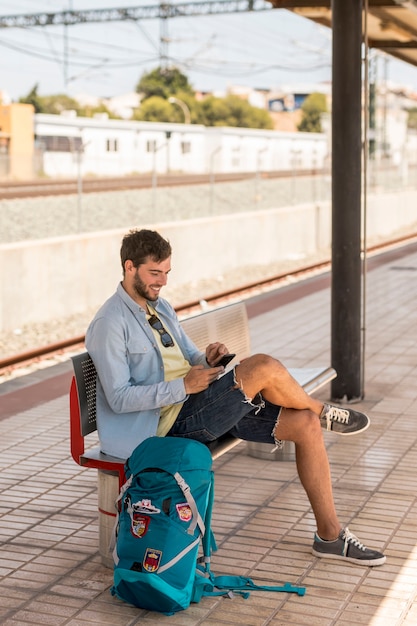 Pasażer uśmiecha się na telefon w stacji kolejowej
