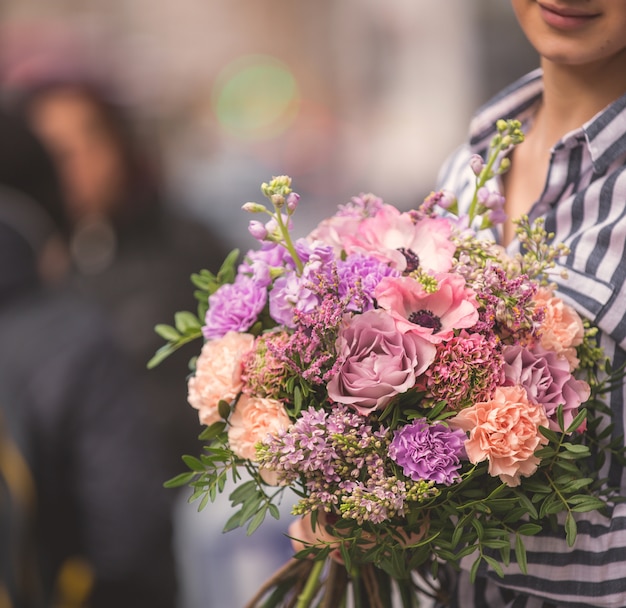 Pastelowy i jasny bukiet kwiatów przytulony przez panią na ulicy