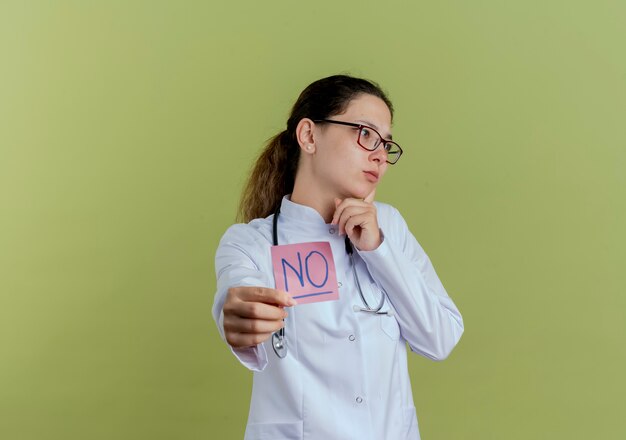 Patrząc na stronę młoda kobieta lekarz ubrana w szlafrok i stetoskop w okularach wyciągając papierową notatkę na białym tle