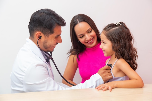 Pediatria płci męskiej bada dziecko dziewczynka stetoskopem, aby sprawdzić płuca i serce. matka zabiera małą dziewczynkę do pediatrii.