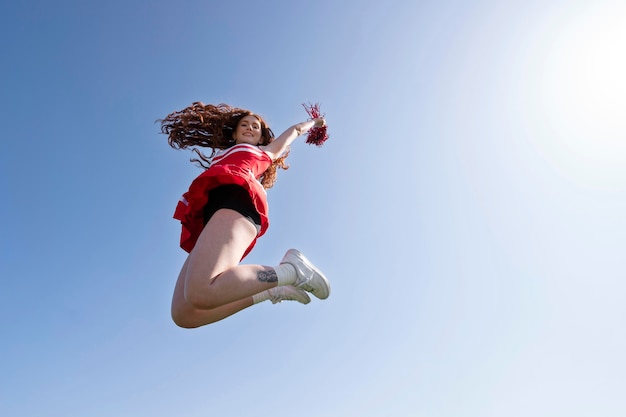 Bezpłatne zdjęcie pełen strzał cheerleaderka skacząca na zewnątrz