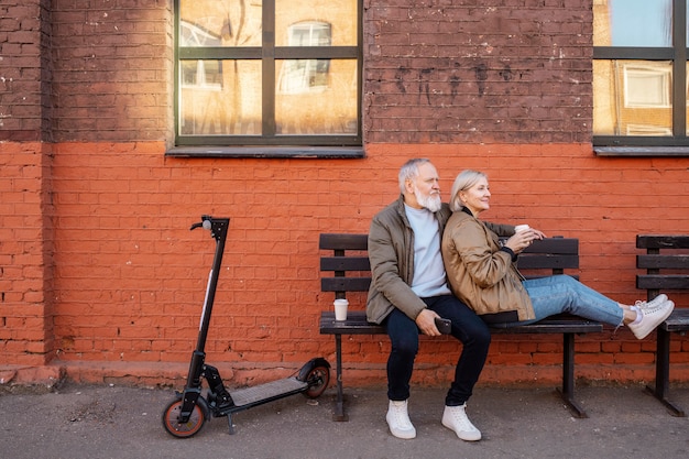 Bezpłatne zdjęcie pełen strzał starsza para siedząca na ławce na zewnątrz