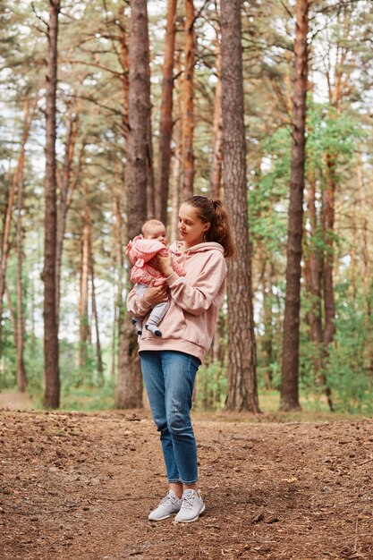 Pełna długość portret młodej dorosłej kobiety z niemowlęcą dziewczyną w rękach