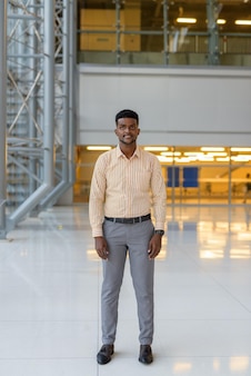 Pełna długość portret przystojnego afrykańskiego mężczyzny w terminalu lotniska podróżującego podczas covid