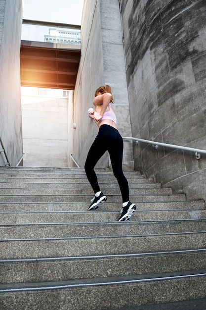 Bezpłatne zdjęcie pełna strzał kobieta biegnąca po schodach