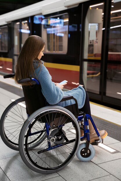 Pełna strzał kobieta na wózku inwalidzkim na stacji metra