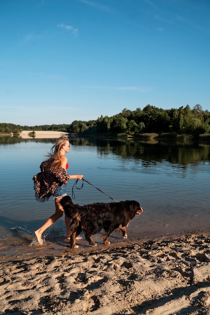 Pełna strzał kobieta spacerująca z psem na plaży