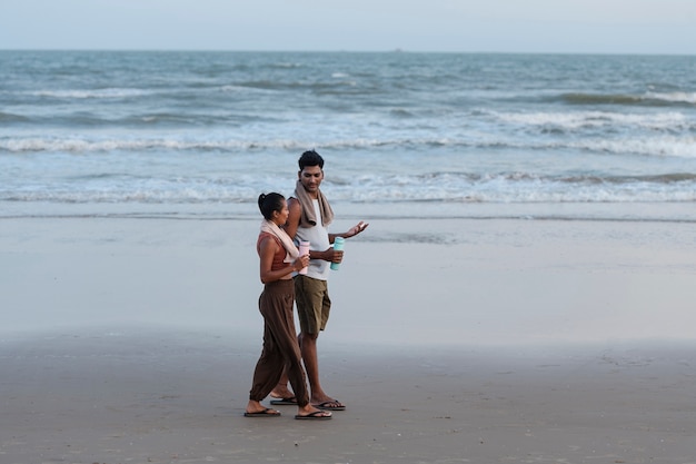 Bezpłatne zdjęcie pełna strzał para spacerująca po plaży?