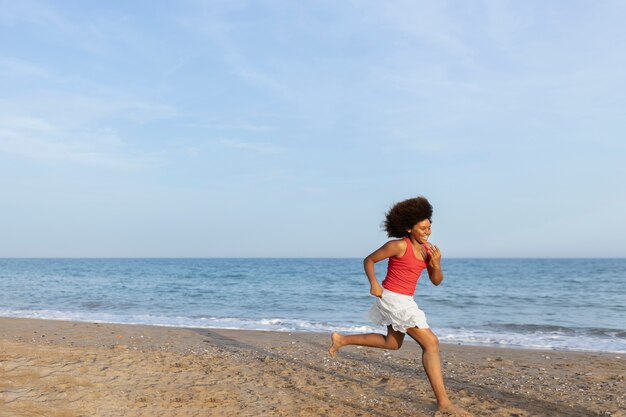 Pełna strzał szczęśliwa dziewczyna biegająca na plaży