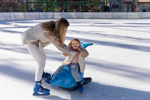 Pełna strzał szczęśliwa matka z dzieckiem na lodowisku