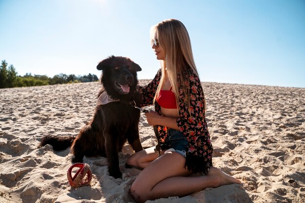 Pełna uśmiechnięta kobieta z psem na plaży