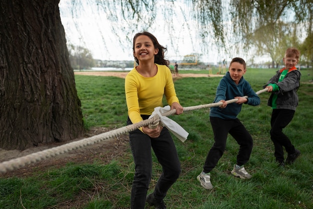 Pełne ujęcie dzieci bawiących się w przeciąganie liny w parku