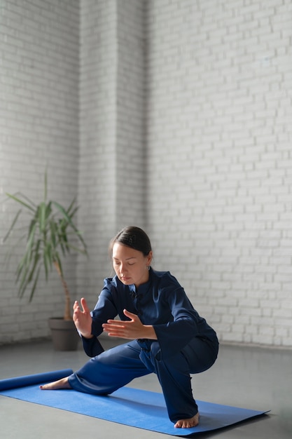 Bezpłatne zdjęcie pełne ujęcie kobiety ćwiczącej tai chi w pomieszczeniu