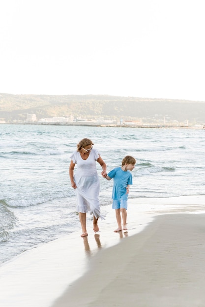 Pełne ujęcie kobiety i dzieciaka na plaży