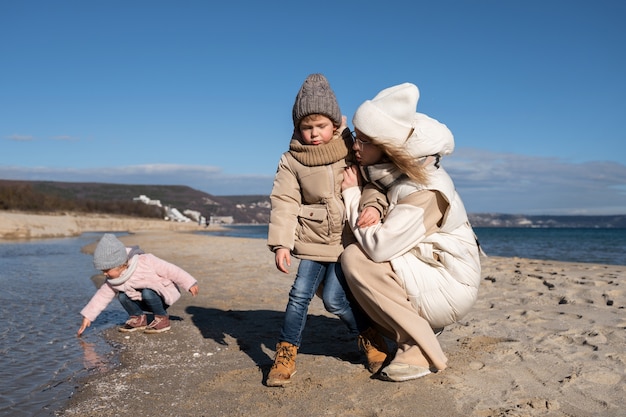 Pełne ujęcie matki i dzieci na plaży