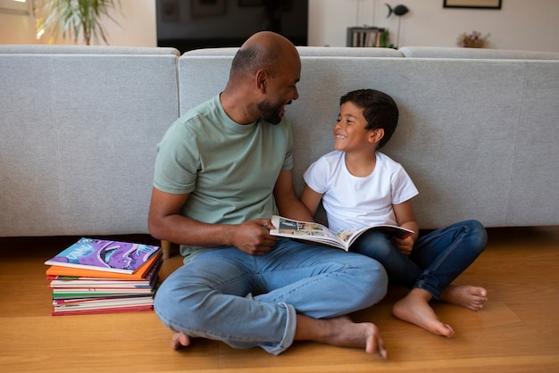 Pełne ujęcie mężczyzny i chłopca czytających komiksy w domu