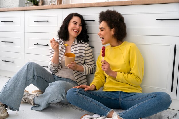 Pełne ujęcie przyjaciół jedzących lody w pomieszczeniu