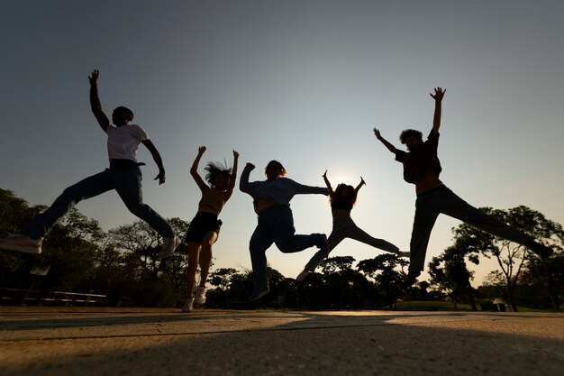 Pełne ujęcie sylwetki przyjaciół skaczących o zachodzie słońca