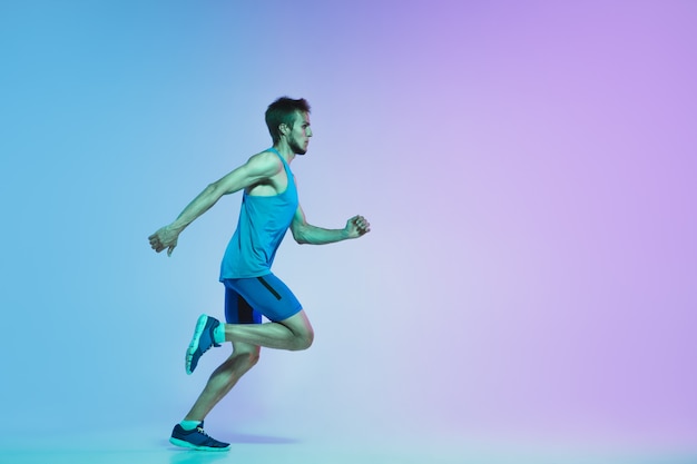Pełnej długości portret aktywnego młodego kaukaskiego biegania, joggingowego mężczyzny w neonowym