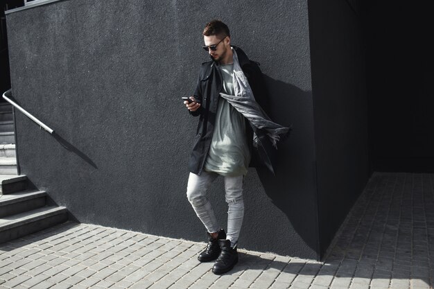 Pełnej długości zdjęcie mężczyzny w płaszczu wiadomość SMS na zewnątrz.