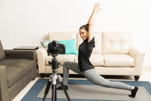 Pełnowymiarowy portret całkiem młodej vlogerki fitness wykonującej jogę przed kamerą