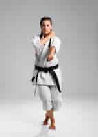 Bezpłatne zdjęcie pełny długość strzał kobieta z czarnym pasem i kimonem ćwiczy karate