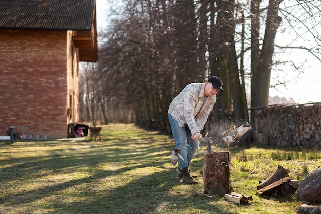 Pełny strzał człowieka rozłupującego drewno na zewnątrz