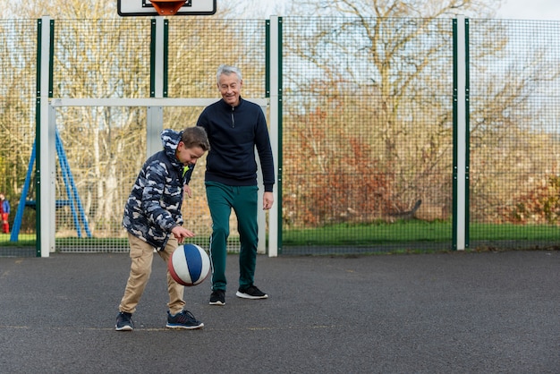 Pełny strzał dziadek i dzieciak grający w koszykówkę