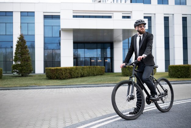 Pełny strzał, elegancki mężczyzna idący do pracy na rowerze