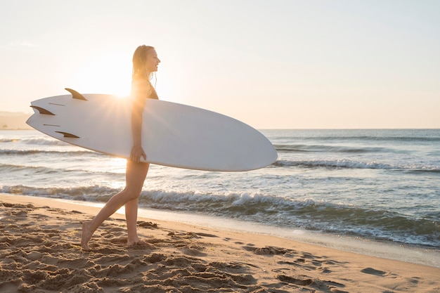 Bezpłatne zdjęcie pełny strzał kobieta trzyma deskę surfingową