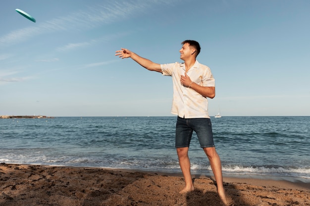 Bezpłatne zdjęcie pełny strzał mężczyzny grającego na plaży?