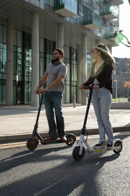 Pełny strzał młodych ludzi na skuterach elektrycznych na zewnątrz