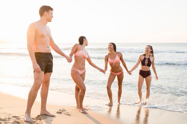 Pełny strzał przyjaciół trzymających się za ręce na plaży