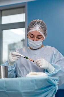 Perspektywa pacjentki na stole operacyjnym, która widzi lekarza powyżej ze strzykawką w dłoni. selektywne skupienie