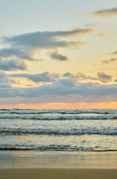 Piaszczysta plaża zachód słońca nad morzem z kolorowymi chmurami pomarańczowe światło słoneczne Pionowa ramka jesienne zachody słońca wczesna jesień aksamitny sezon Pomysł tła lub ekranu powitalnego