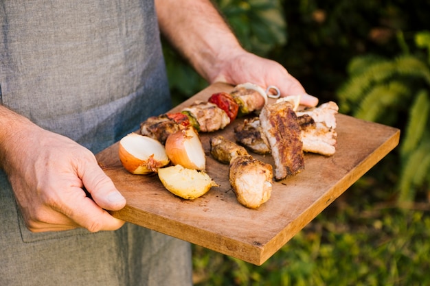Piec na grillu mięso i warzywa na drewnianym biurku w rękach