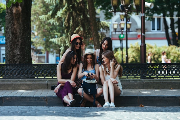 Pięć pięknych młodych dziewczyn rozważa torbę w parku